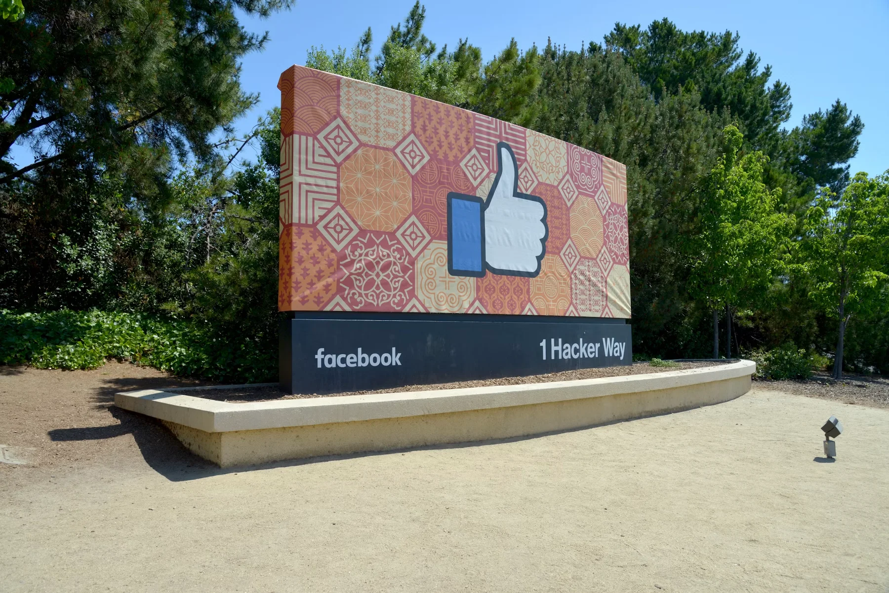 绿树环绕的 Facebook 园区入口,标牌上有点赞图案和 1 Hacker Way 字样