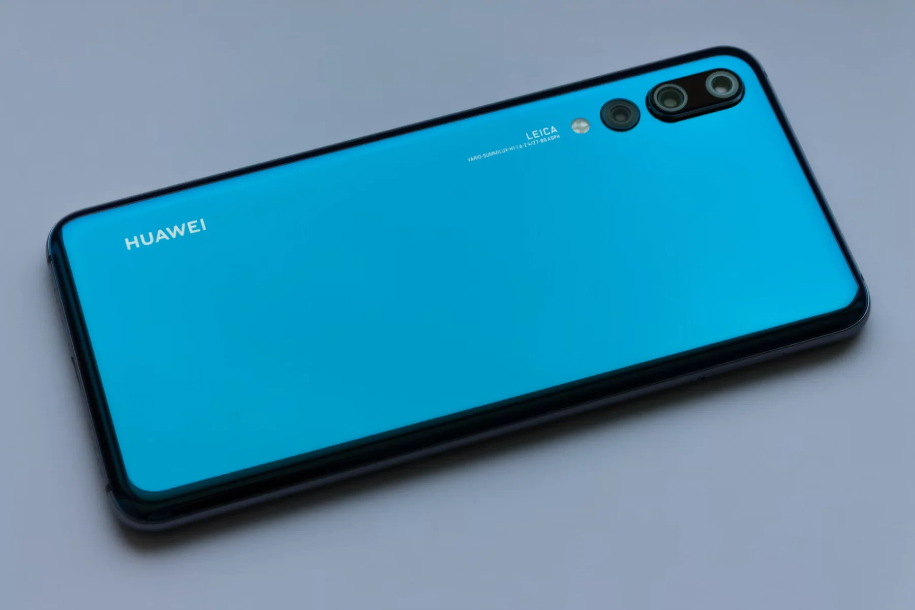 灰色背景上斜放的蓝色华为手机，背面印有 HUAWEI 标志